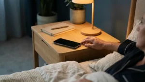 Main près d'un téléphone posé sur une table de nuit pendant un réveil nocturne